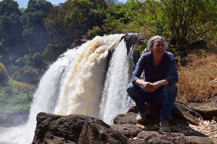 Woman sitting and smiling in front of Blue Nile Falls