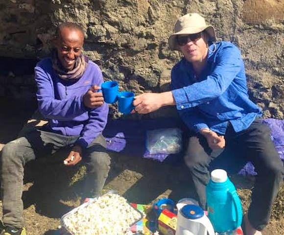 Two men drinking tea while camping in the Simien Mountains