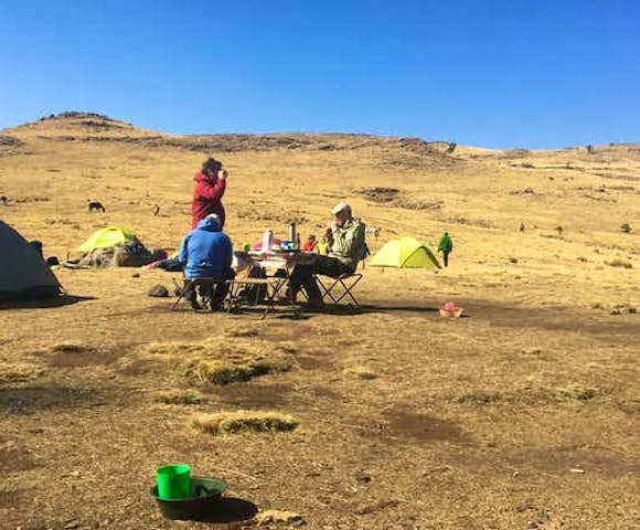 People sitting on bench at a campsite in the Simien Mountains