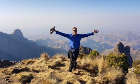 Man spreading arms in front of landscape view in the Simien Mountains